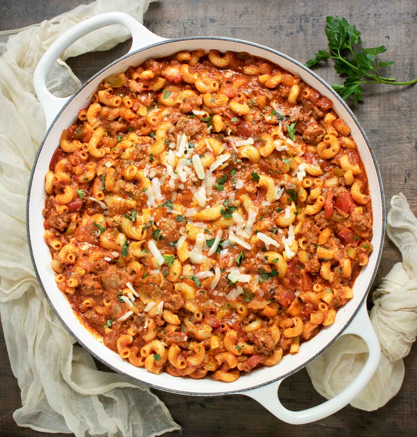 An overhead view of American Goulash, ready to serve, in a large, white braiser.