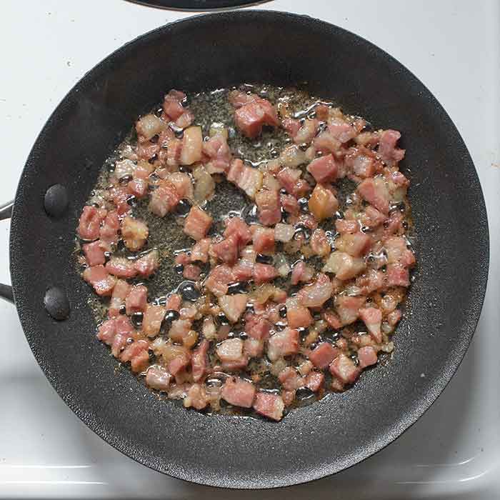 Pancetta frying in a small pan.