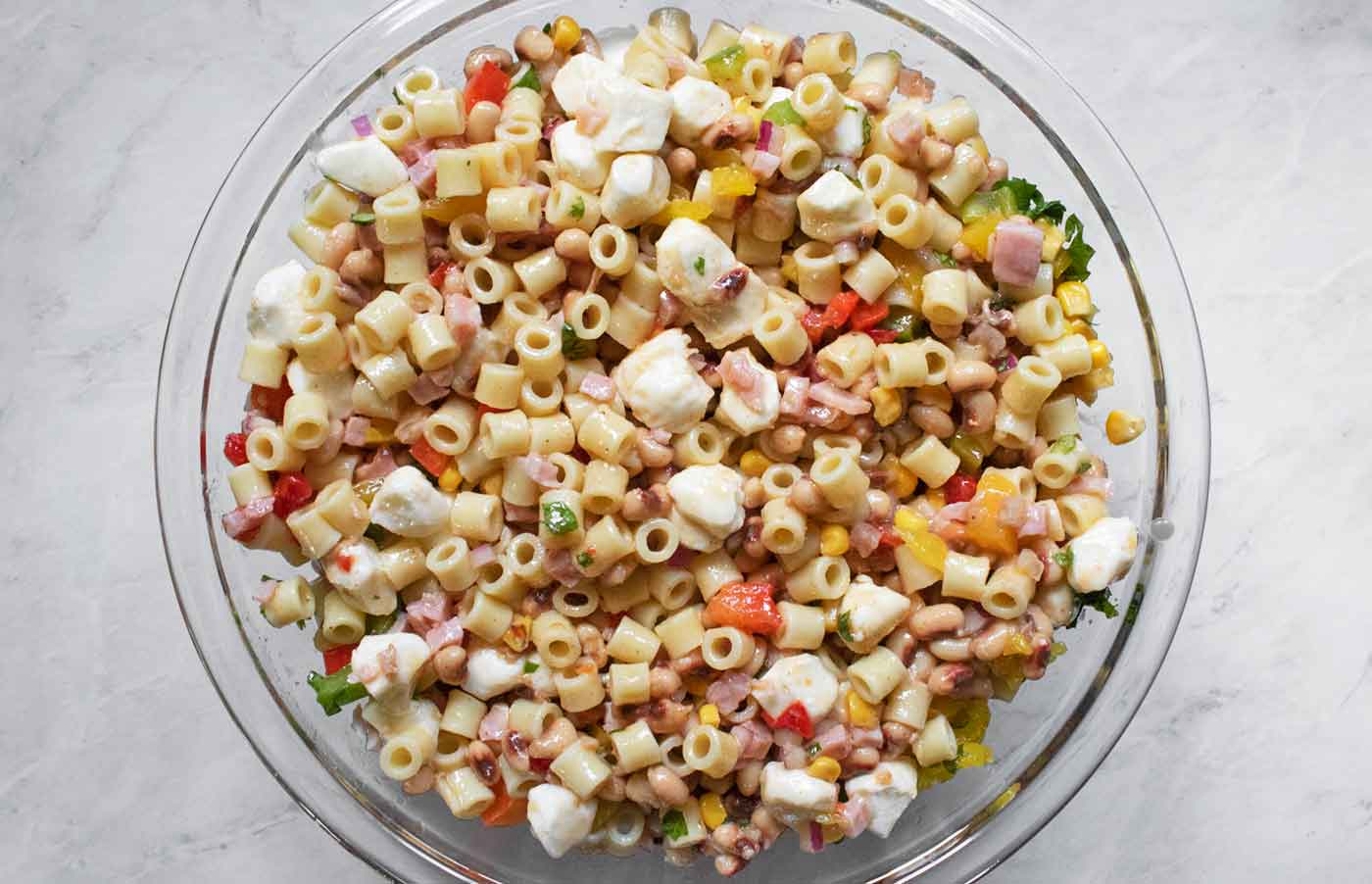 The finished pasta salad, tossed with the vinaigrette, ready to serve from the glass bowl.