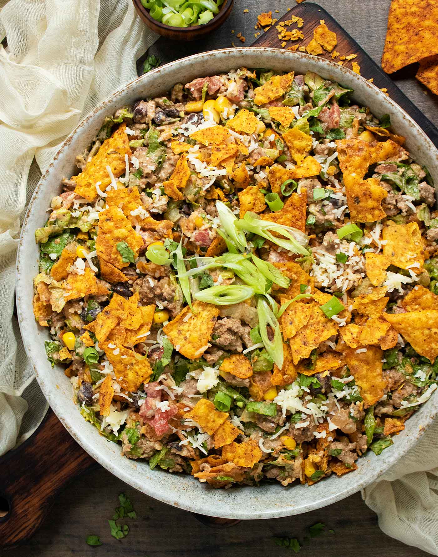 Overhead view of a bowl of Doritos Taco Salad on a wooden board.
