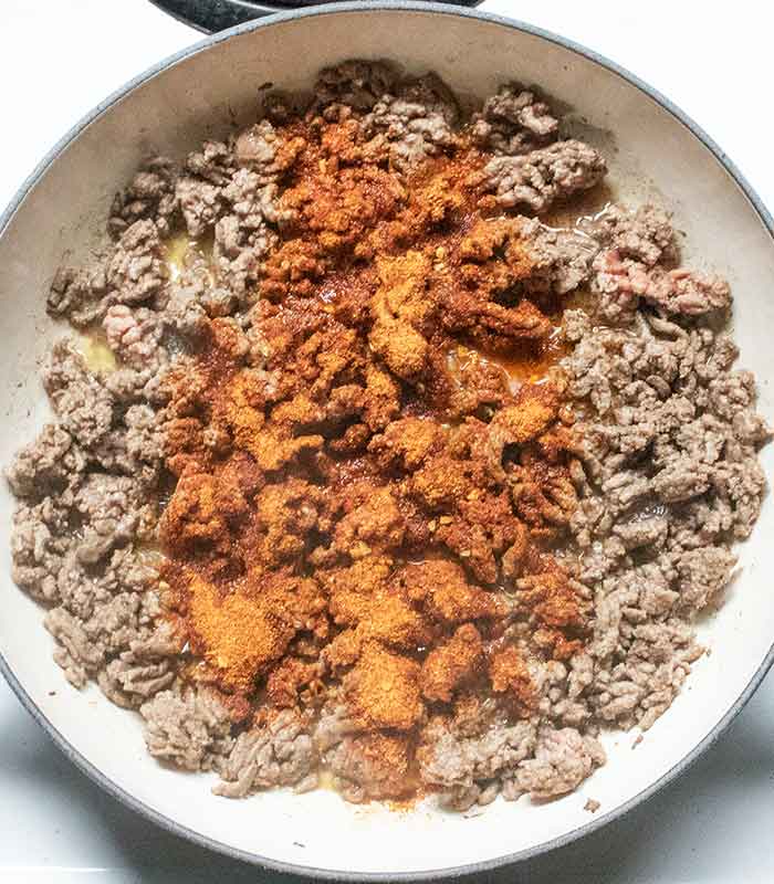 Adding the taco seasoning to the browned ground beef.