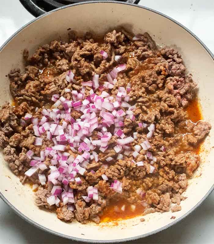 Sauteing the red onions with the ground beef.