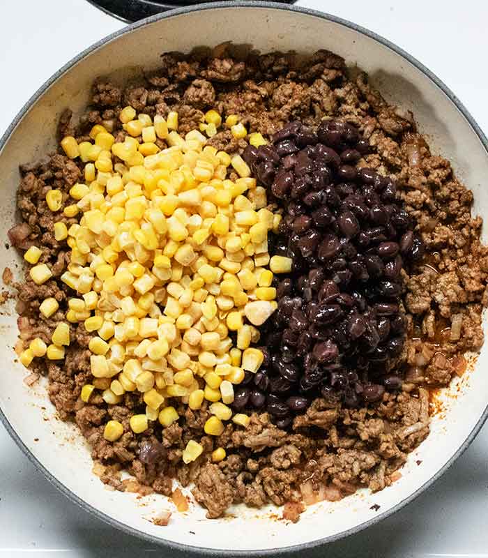 Adding the corn and the beans to the pan.