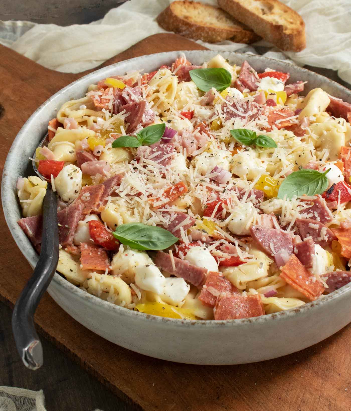 Side-angled view of Italian Grinder Tortellini Salad on a wooden serving board.
