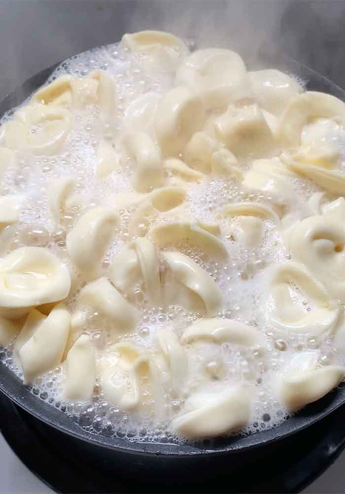 Tortellini pasta boiling in a large pot.