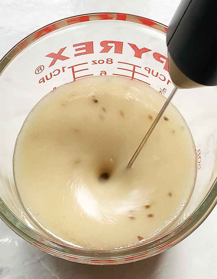 Mixing the dressing ingredients with a milk frother.