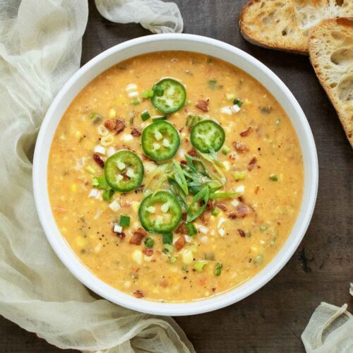 Overhead view of a bowl of Jalapeno Bacon Corn Chowder with slices of toasted bread on the side and napkins.