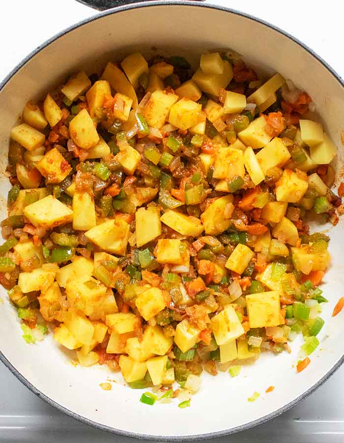 Adding the cubed potatoes to the vegetable mixer.