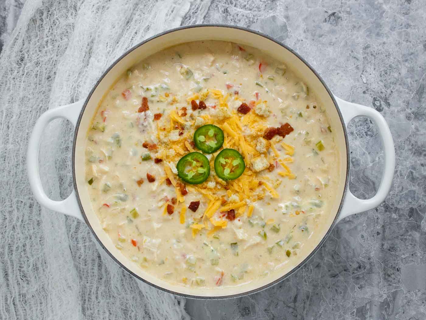 Overhead view of Jalapeno Popper Chicken Soup in a large white Dutch oven.