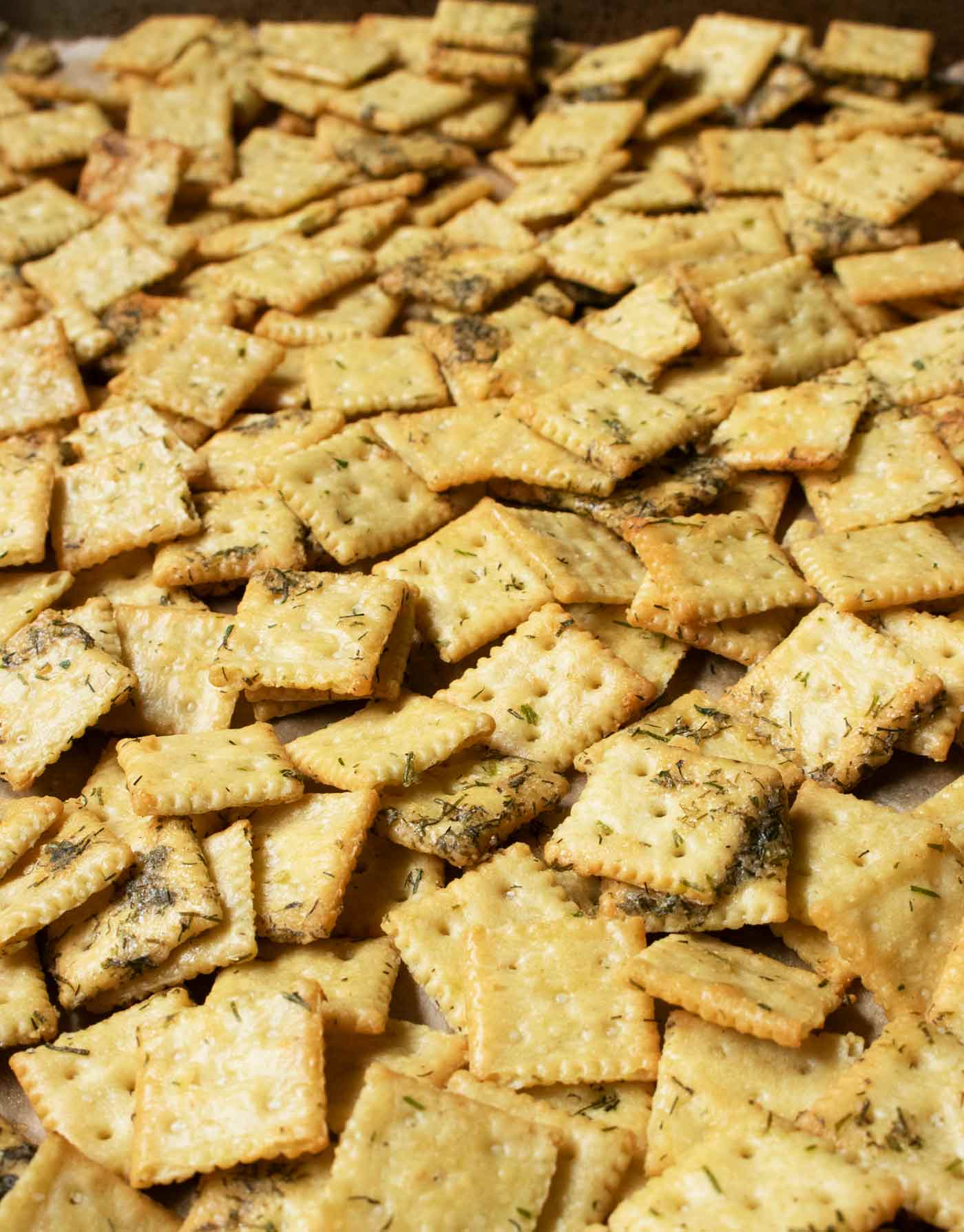 Lots of Dill Pickle Saltines spread out on a large baking sheet.