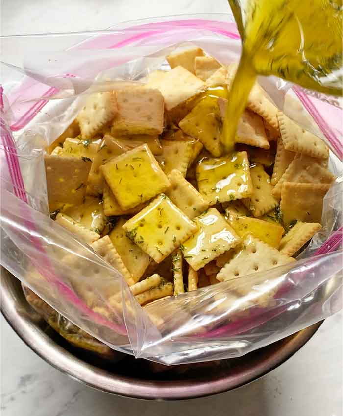 Pouring the marinade over the crackers in the bag.