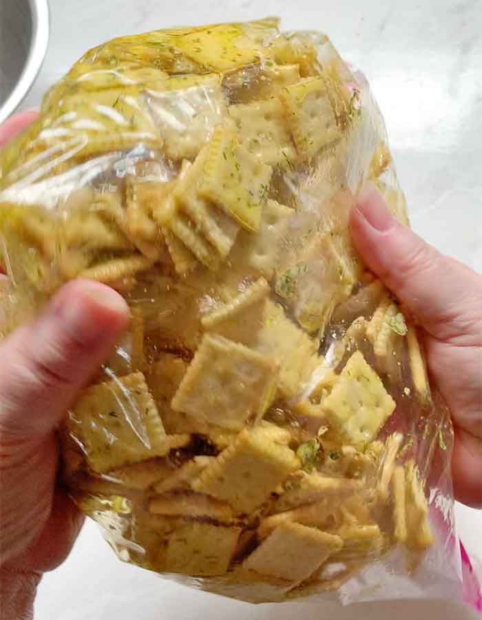 Turning the crackers over and over in the sealed bag to distribute the marinade.