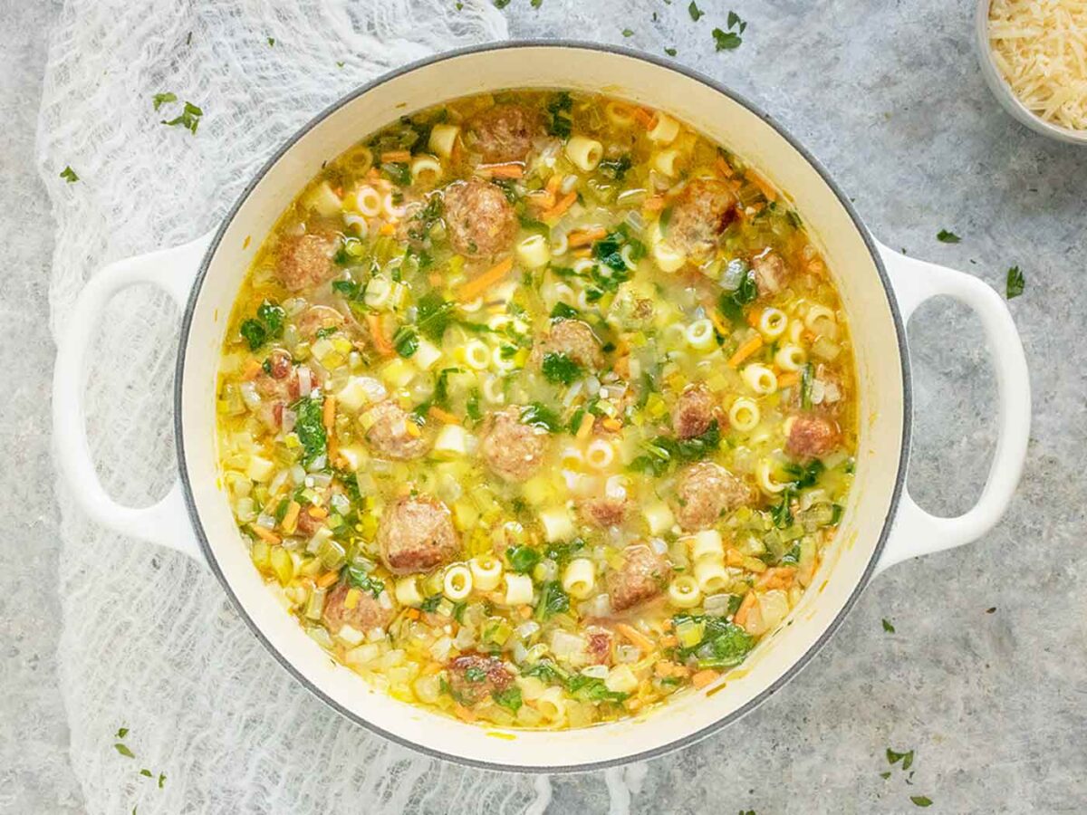 Overhead view of Italian Wedding Soup in a white Dutch oven.