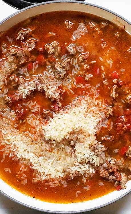 Adding the rice and broth to the skillet.