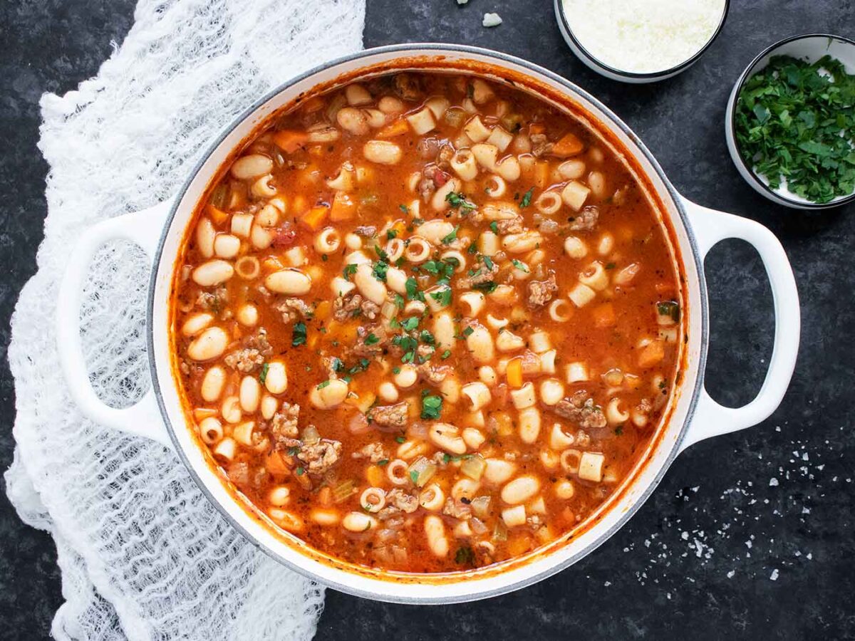 Overhead view of Pasta e Fagioli in a large white Dutch oven.