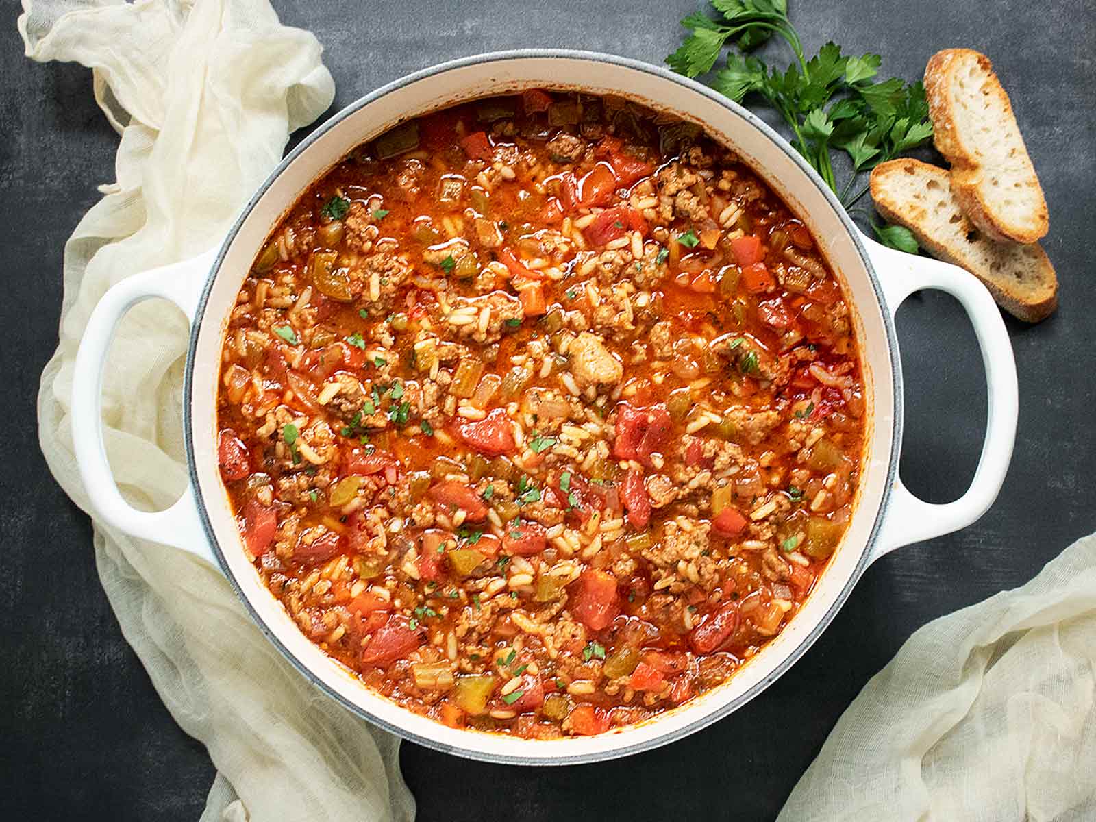 Overhead view of Stuffed Pepper Soup in a large white Dutch oven with bread slices on the side.