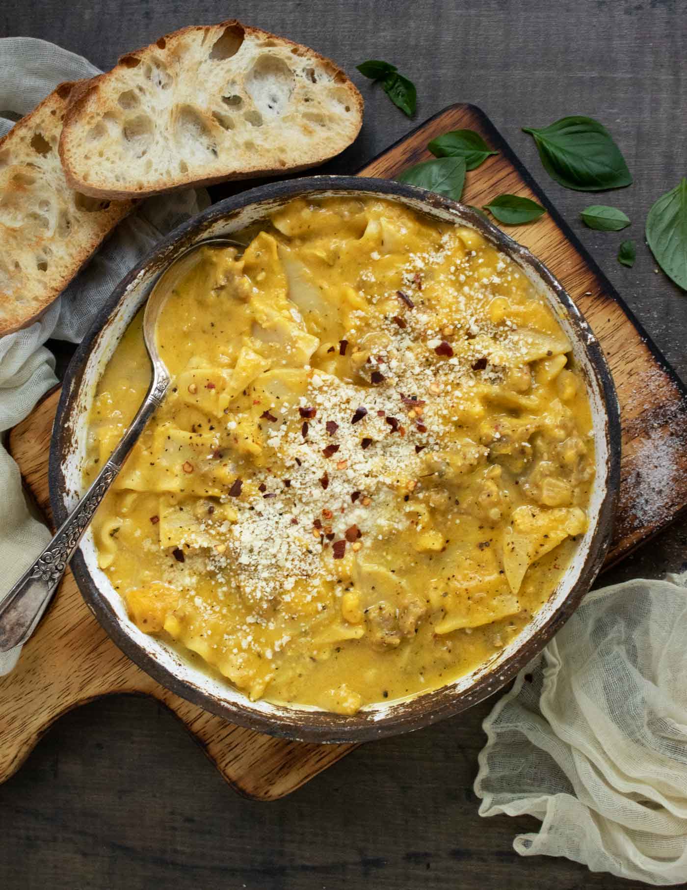 Overhead view of Butternut Squash Lasagna Soup in a bowl on a wooden board with toasty bread slices on the side.