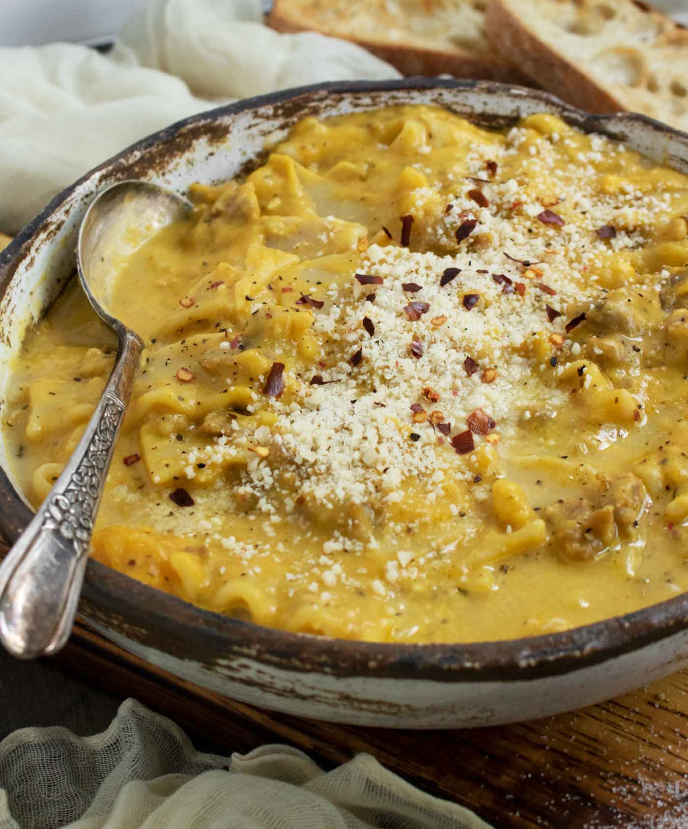 Side-angled view of a bowl of Butternut Squash Lasagna Soup in a white ceramic bowl with a spoon.