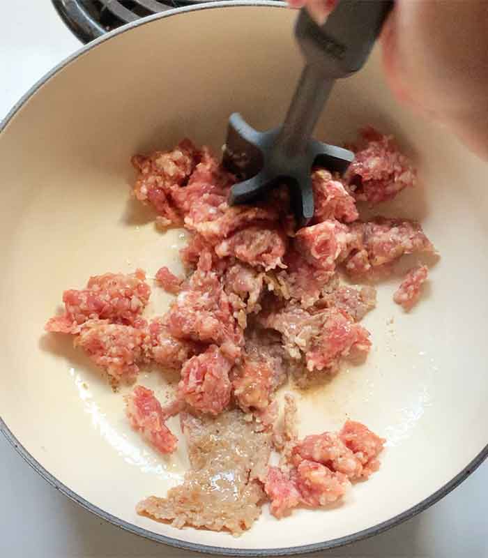 Breaking up the sausage in the pot.