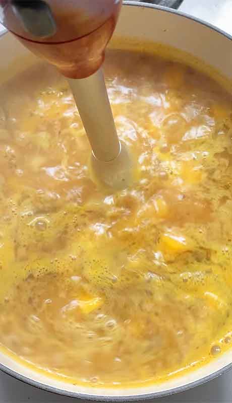 Giving the base a few pulses with an immersion blender to create a creamier soup.