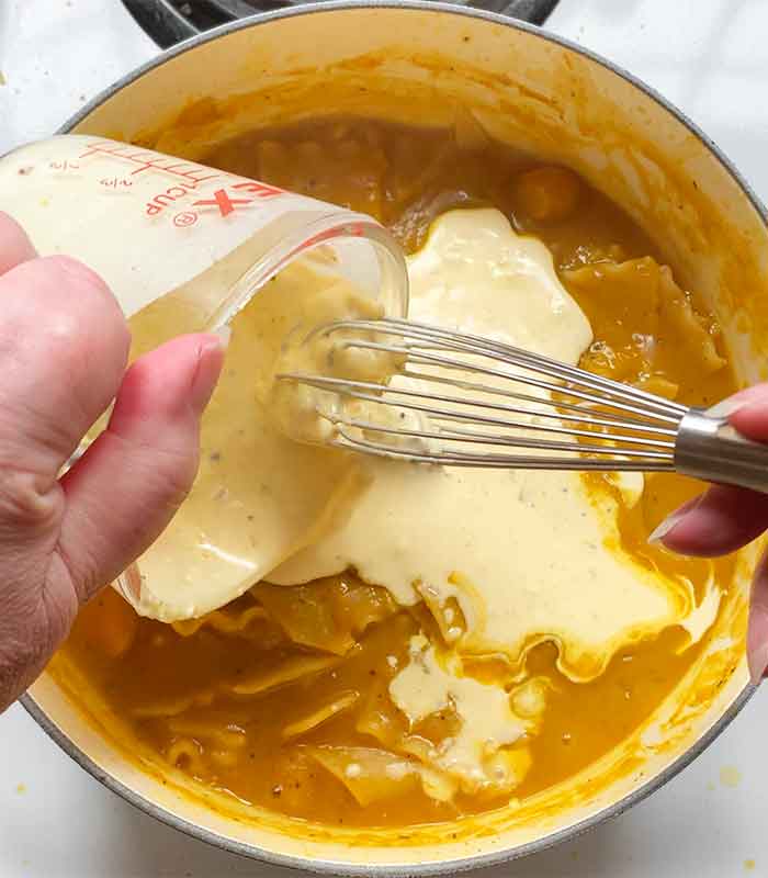 Pouring the Boursin mixture into the soup.