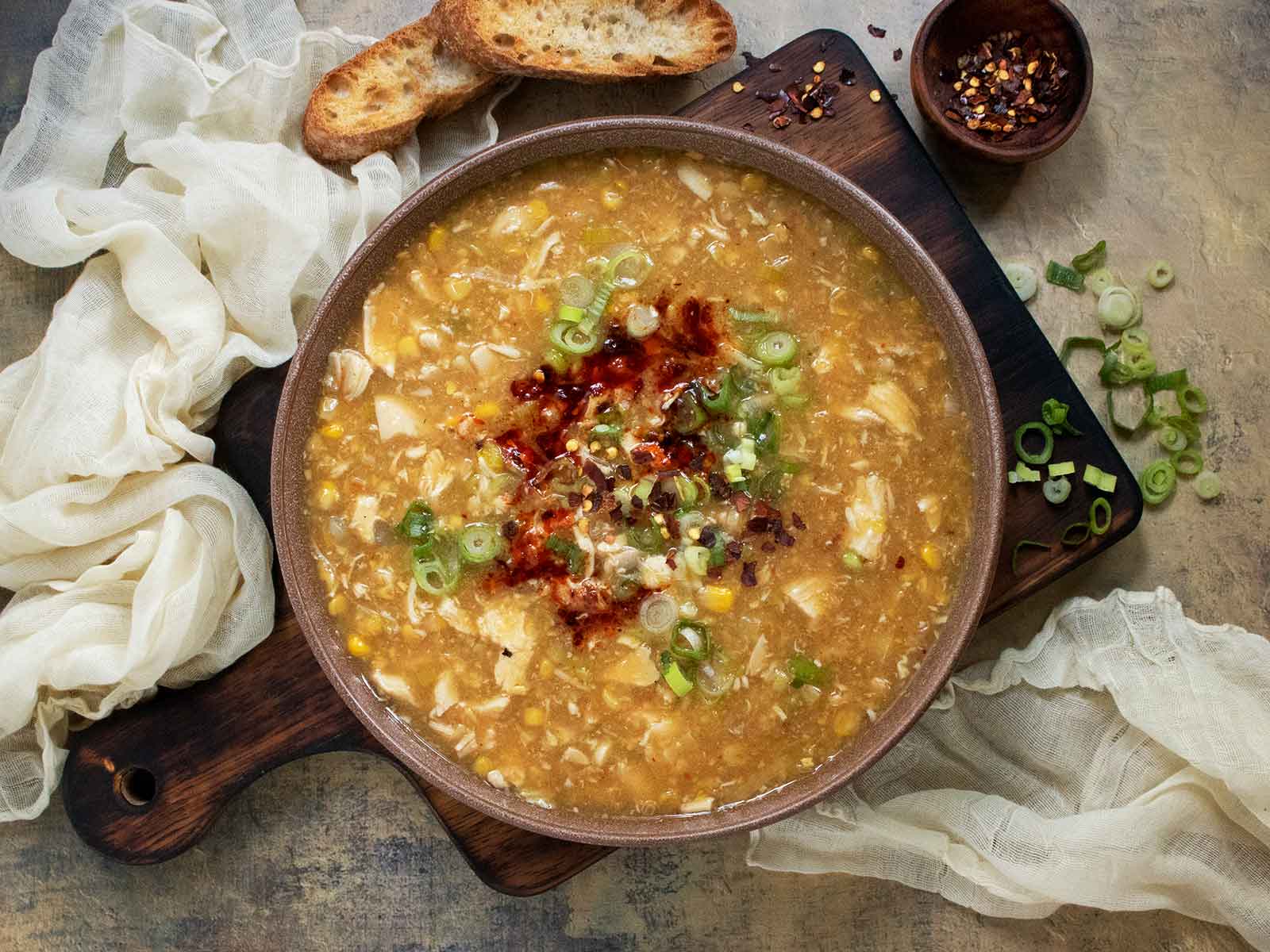 Creamy Chicken and Corn Soup in a bowl on a wooden serving board.
