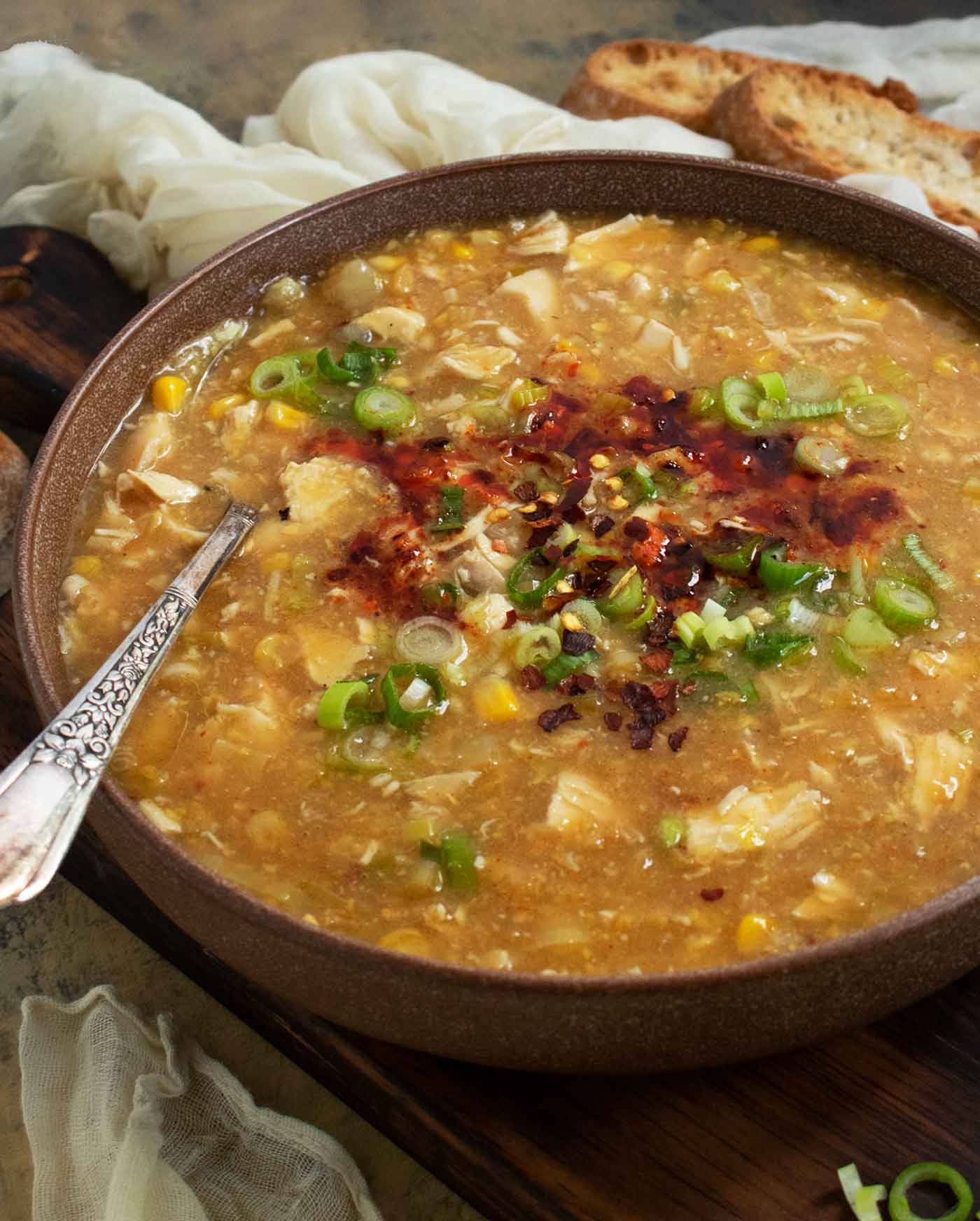 Side-angled view of a bowl of Creamy Chicken and Corn Soup with a spoon.