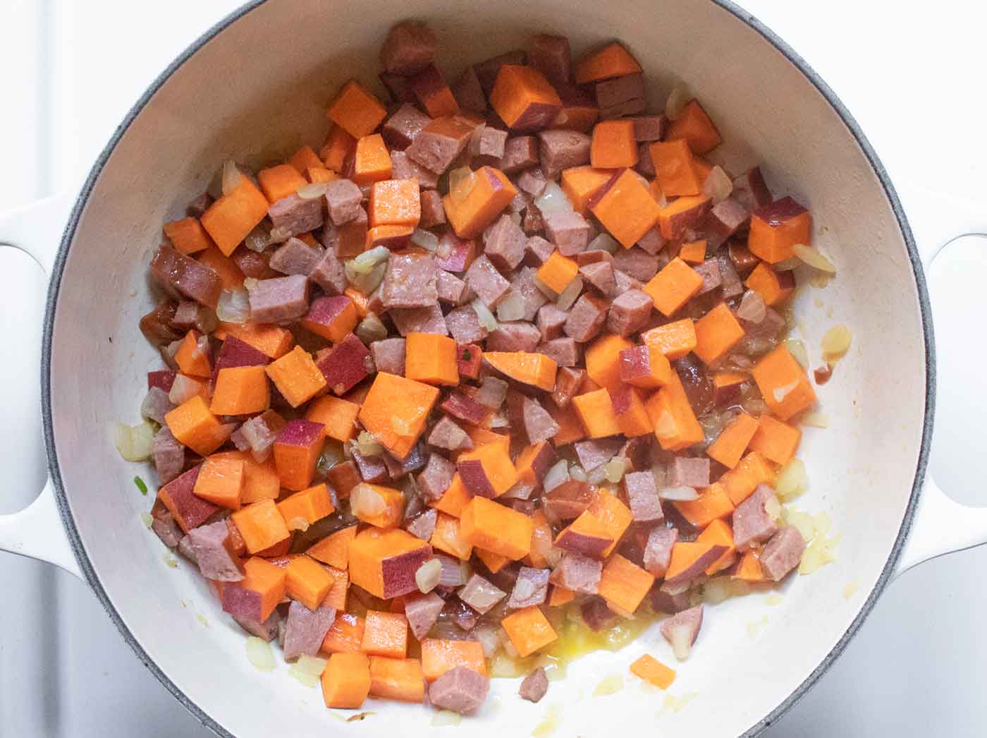 Onions, sausage, and sweet potatoes cooking in the pot.