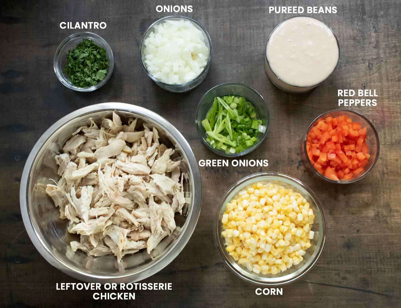 Prepared ingredients for the chili in small glass prep bowls, each labeled with overlay text.