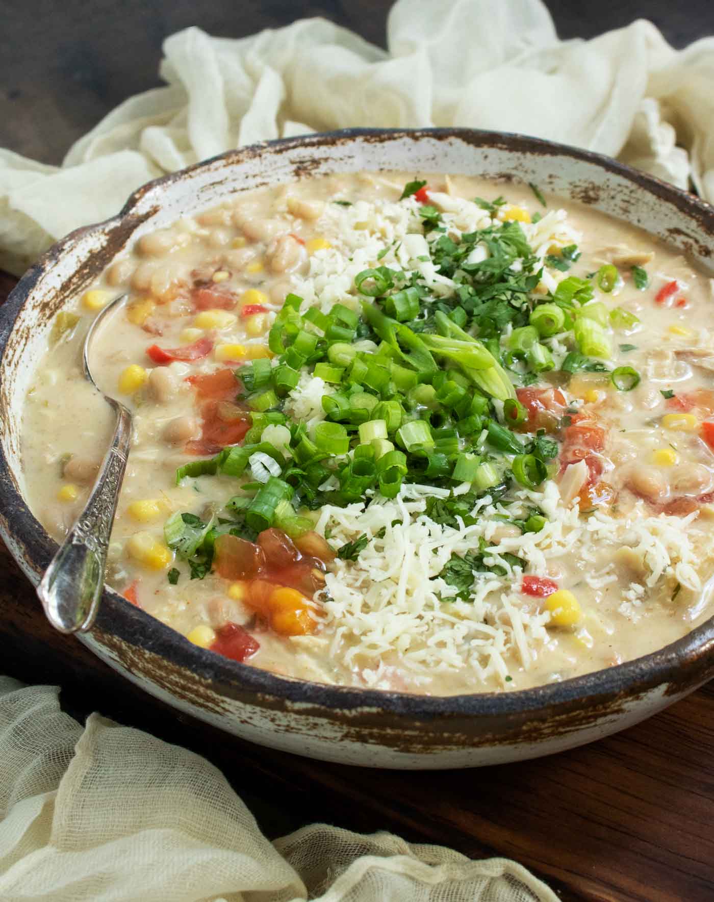 A side-angled view of a bowl of Southwest White Chicken Chili with a spoon.