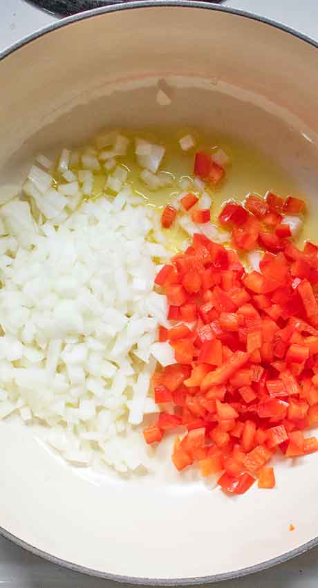 Onions and red bell peppers sauteeing in a little bit of oil.