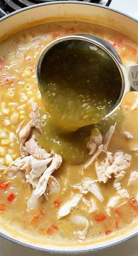Adding shredded chicken, corn, and the salsa verde to the pot.