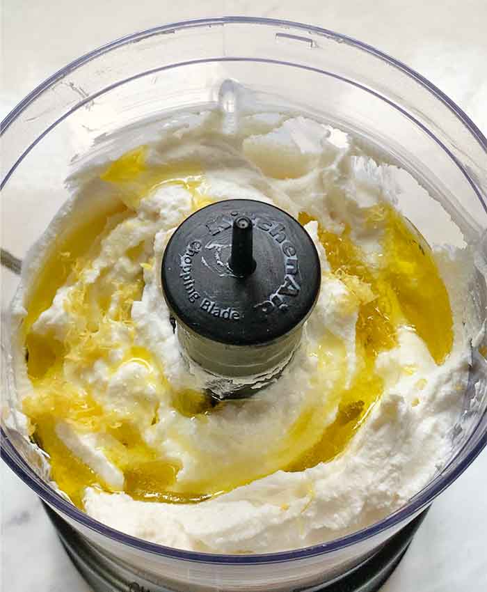 Ricotta in the bowl of a food processor, ready to be whipped.