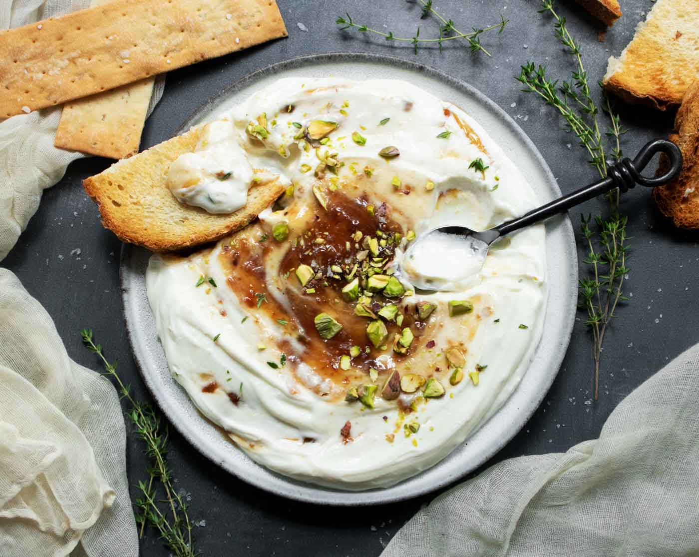 The finished dip with a toasted triangle schmeared with some of the dip, and a spoon on the side.