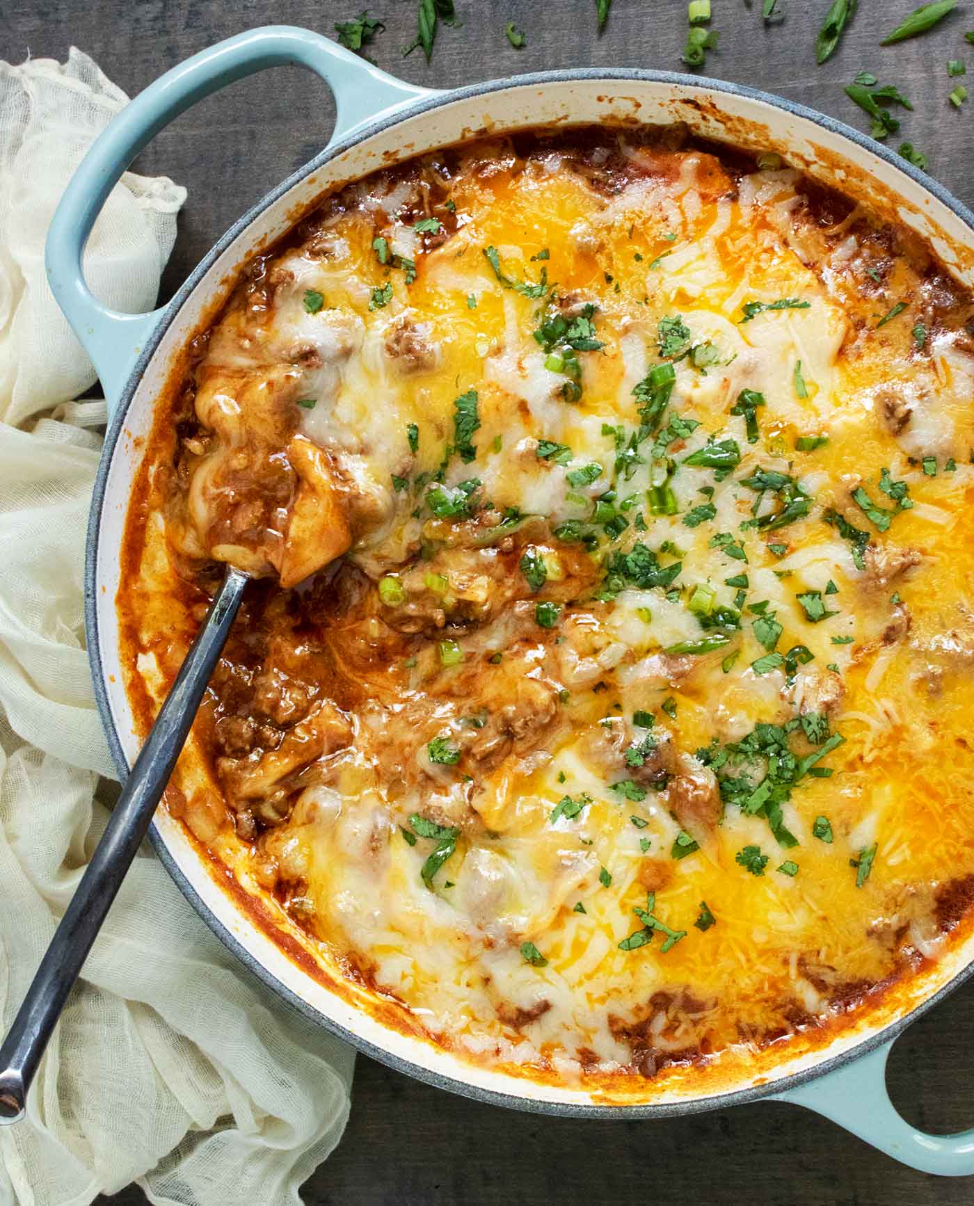 Overhead view of Cheesy Beef Enchilada Skillet with a serving spoon.
