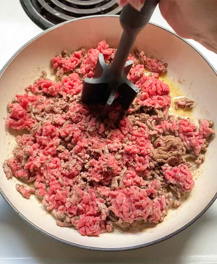 Breaking up the ground beef in the skillet with a star-tipped meat masher thingy.