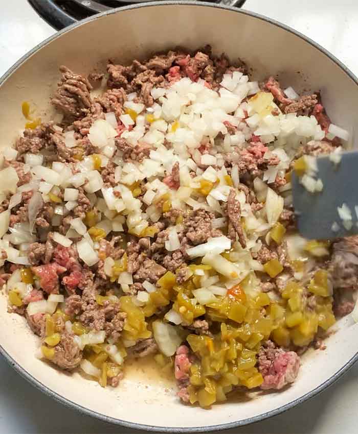Stirring the onions and green chiles into the beef with a gray spurtle (yes, I said spurtle!).