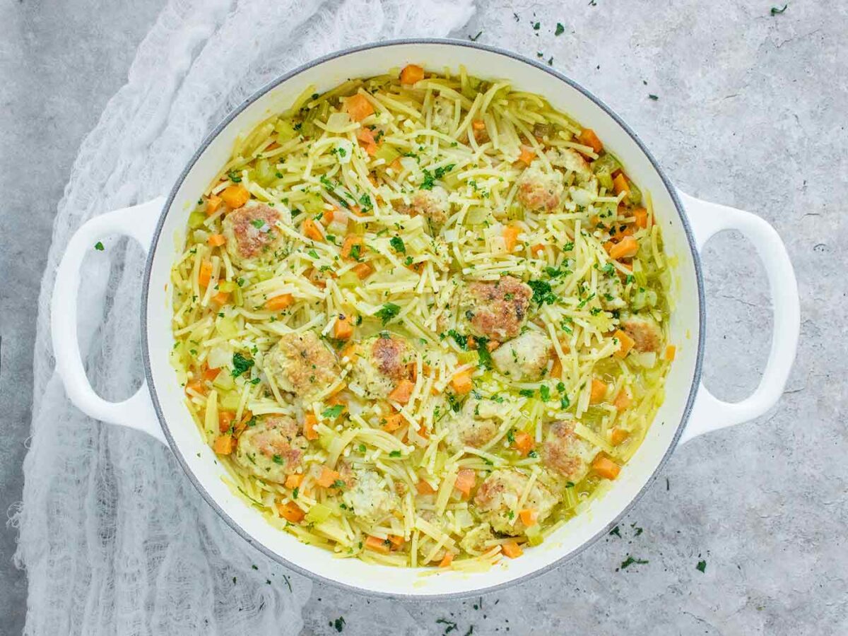 Overhead view of Chicken Meatball Noodle Soup in a large white Dutch oven.