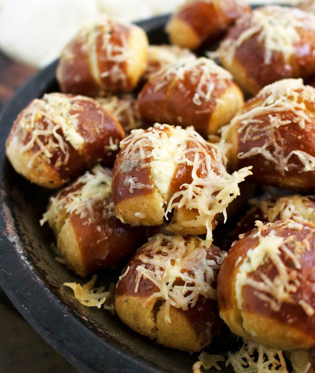 Side-angled view of Cream Cheese Stuffed Ranch Pretzel Bites on a plate, with a close-up of one yummy bite.