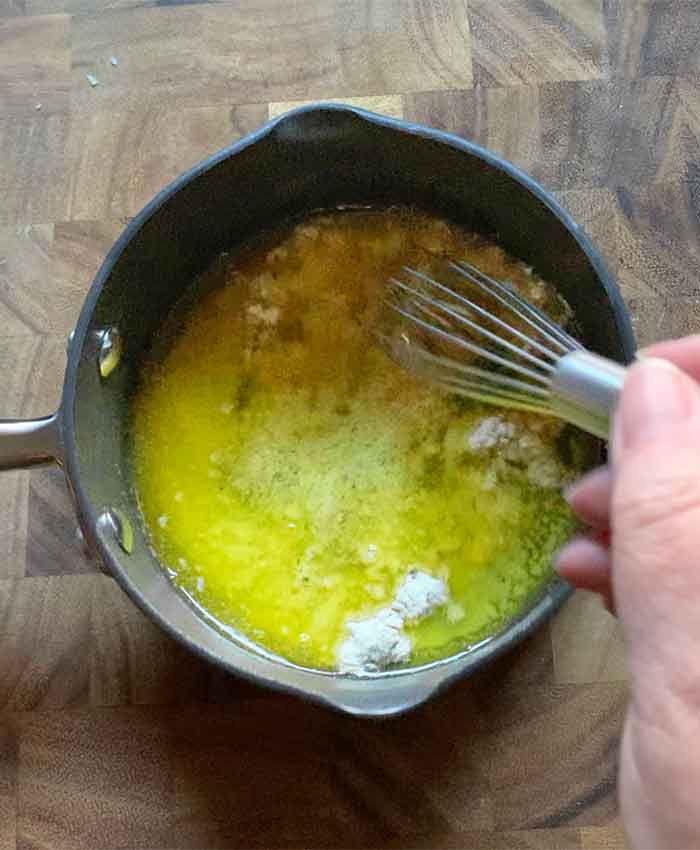 Whisking the ranch seasoning mix into the melted butter.