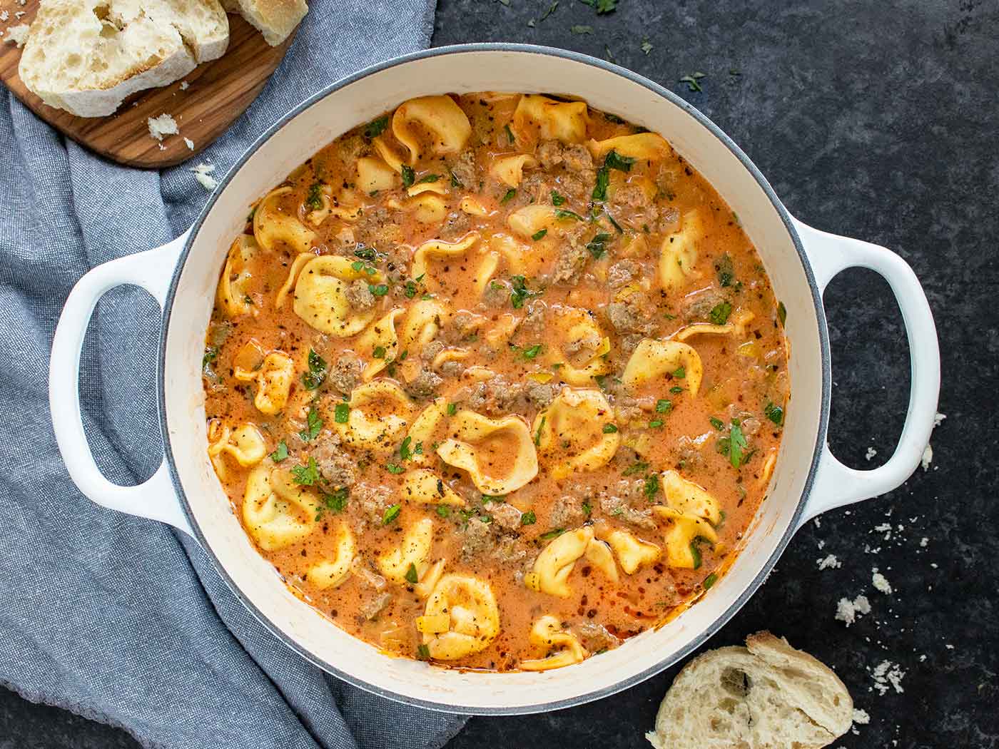Overhead view of Creamy Tortellini Soup in a white Dutch oven.