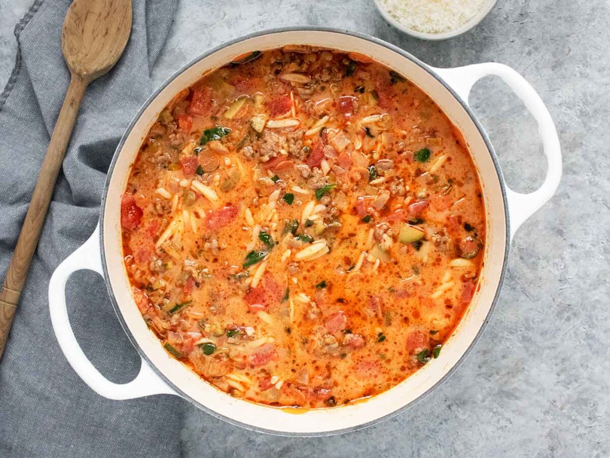 Overhead view of Italian Sausage Orzo Soup in a large white pot.