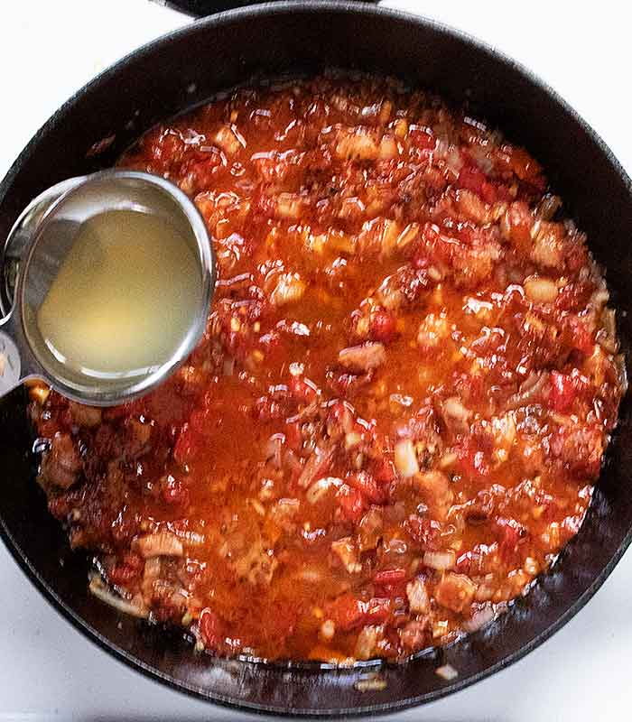 Adding the broth to the skillet.