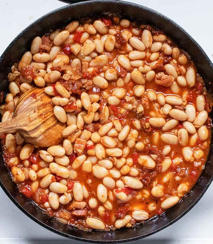 Mixing in the white beans with a pretty wooden spoon.