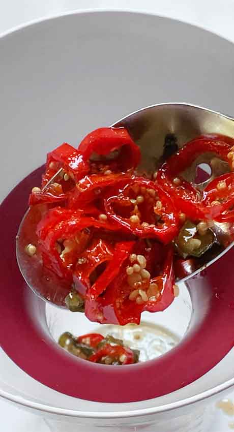 Transferring jalapenos to a jar with the help of a funnel.
