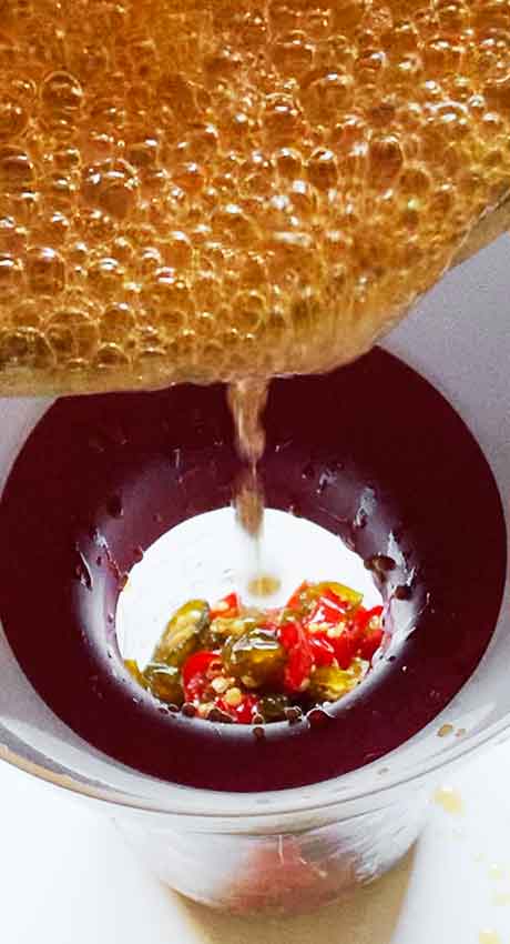 Pouring the brine into the jar through a funnel.