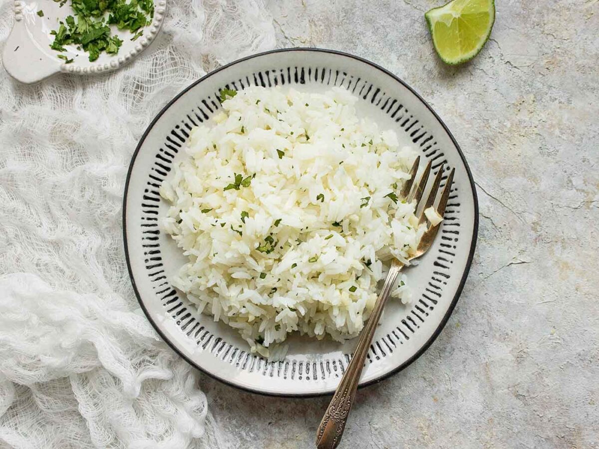 Cauliflower Rice Blend on a white plate with a black edge and a fork digging in.