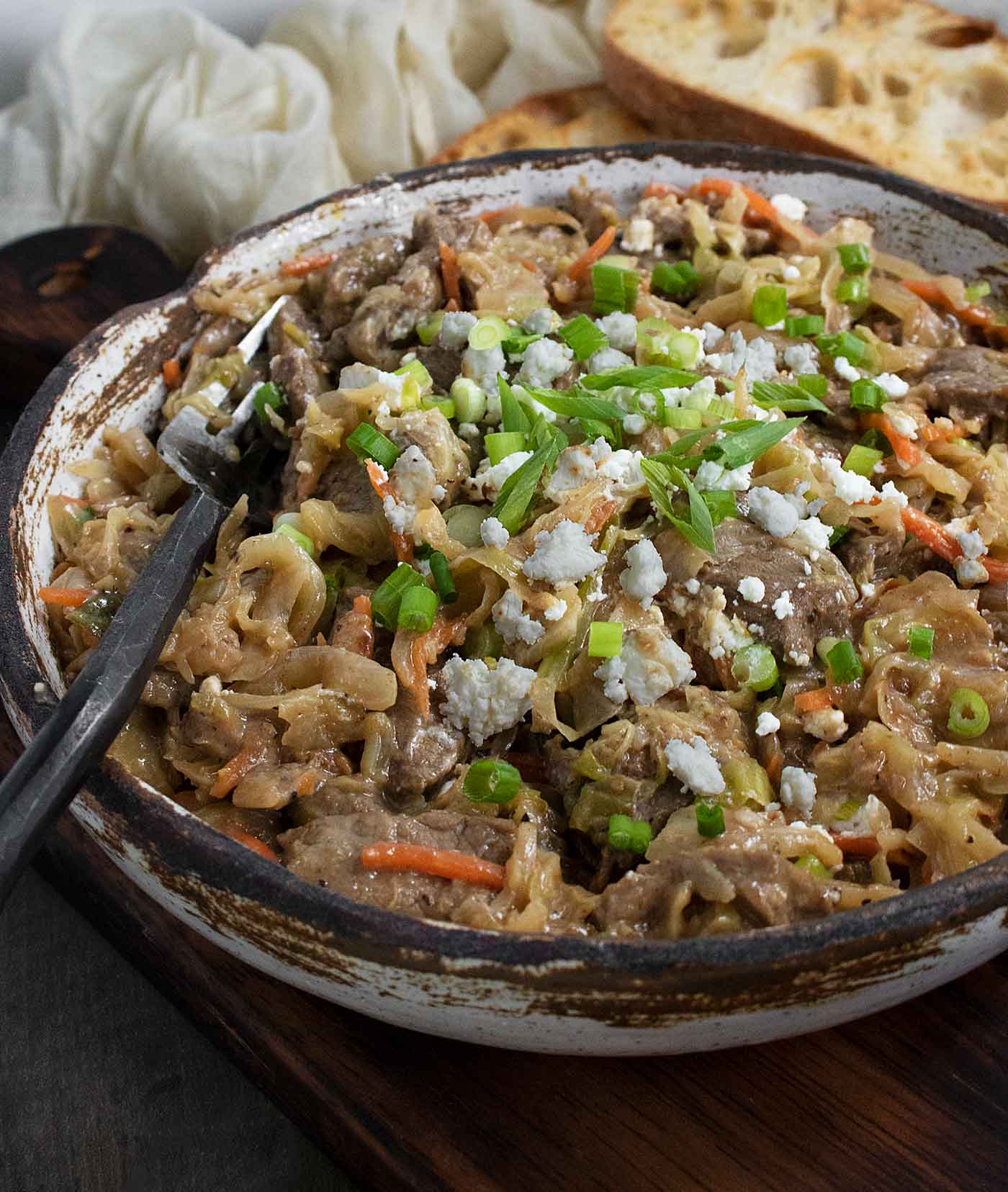 Side-angled view of Steak and Cabbage in a rustic bowl, with a fork.