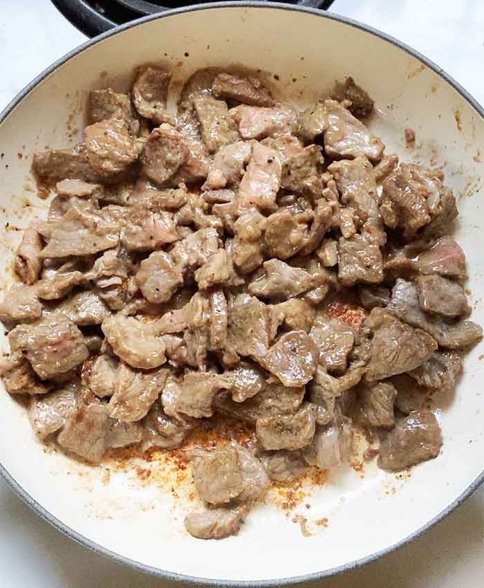 Steak strips cooking in a skillet.