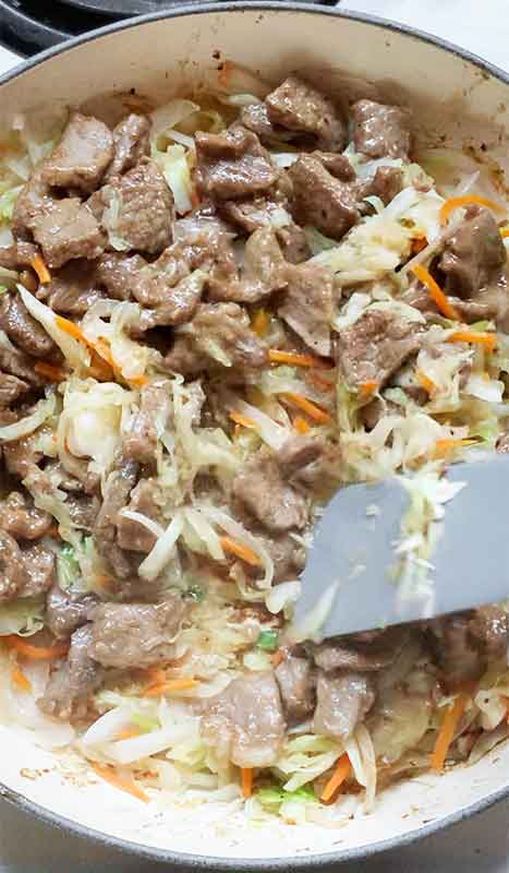 Returning the steak back to the skillet to mix with the cabbage.